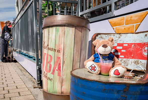 Teddybär mit Freiburgwappen auf dem Fuß sitzt auf dem Geländer der Mess'